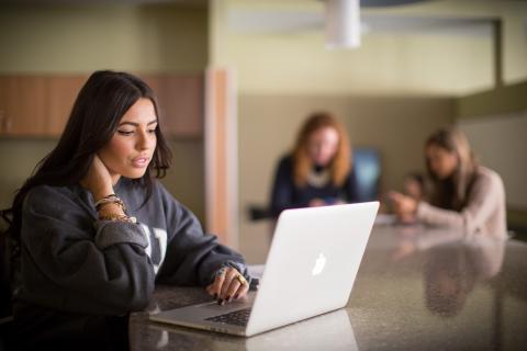 学生坐在桌子旁看着他们的笔记本电脑